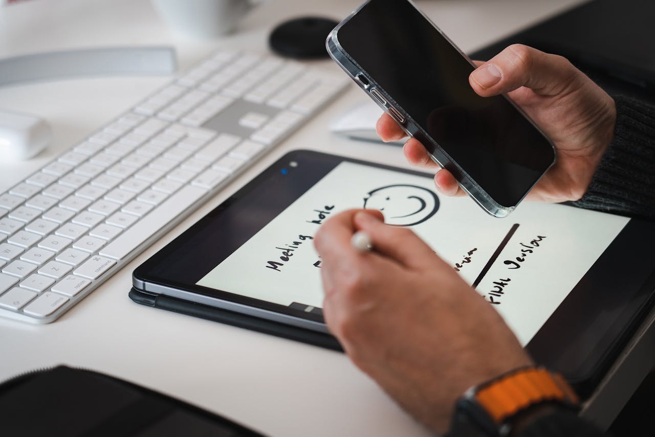 Contact Hands using a stylus on a tablet for note-taking alongside a smartphone, suitable for tech themes.